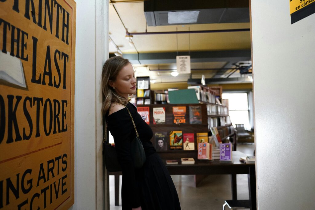 A young woman leaning on a wall inside The Last Bookstore in Los Angeles.